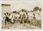 Čiabuvis su bumerangais ir grupė vaikų Australijos gyvenvietėje